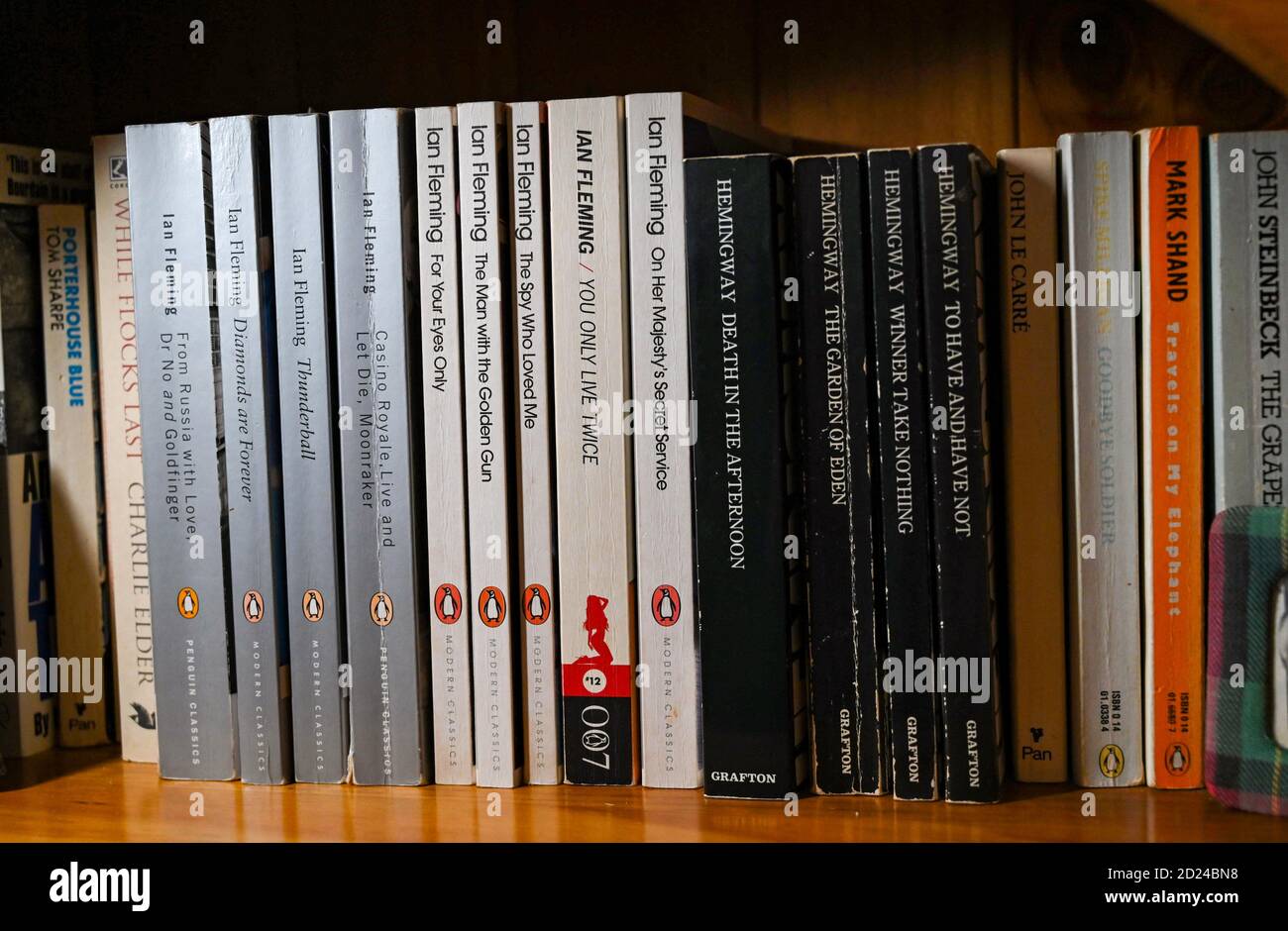 James Bond spy novels written by author Ian Fleming and Ernest Hemingway books on home bookshelf Stock Photo