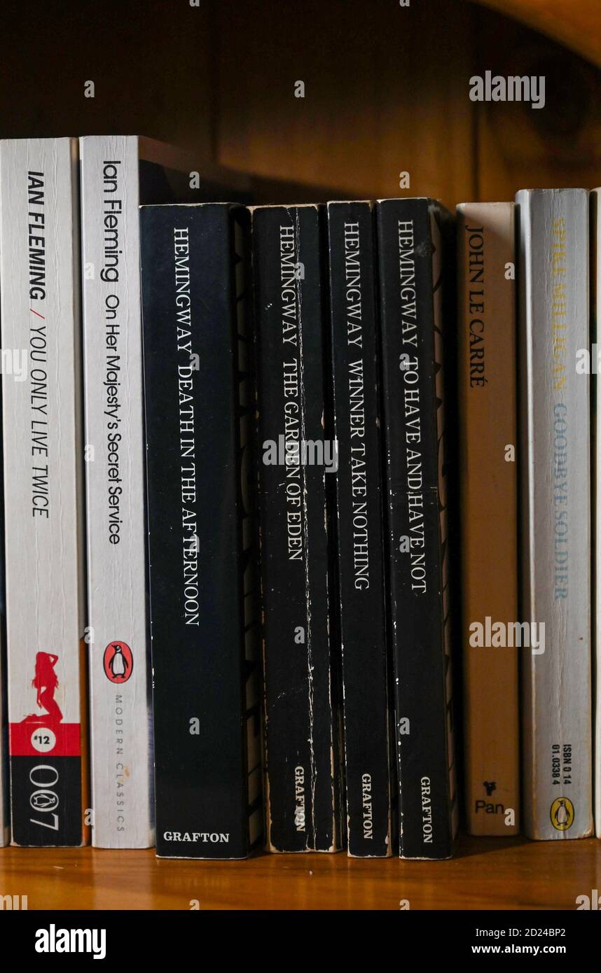 James Bond spy novels written by author Ian Fleming and Ernest Hemingway books on home bookshelf Stock Photo