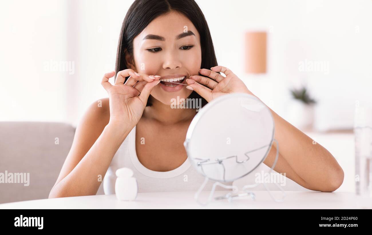 Young asian woman using dental floss looking in mirror Stock Photo Alamy