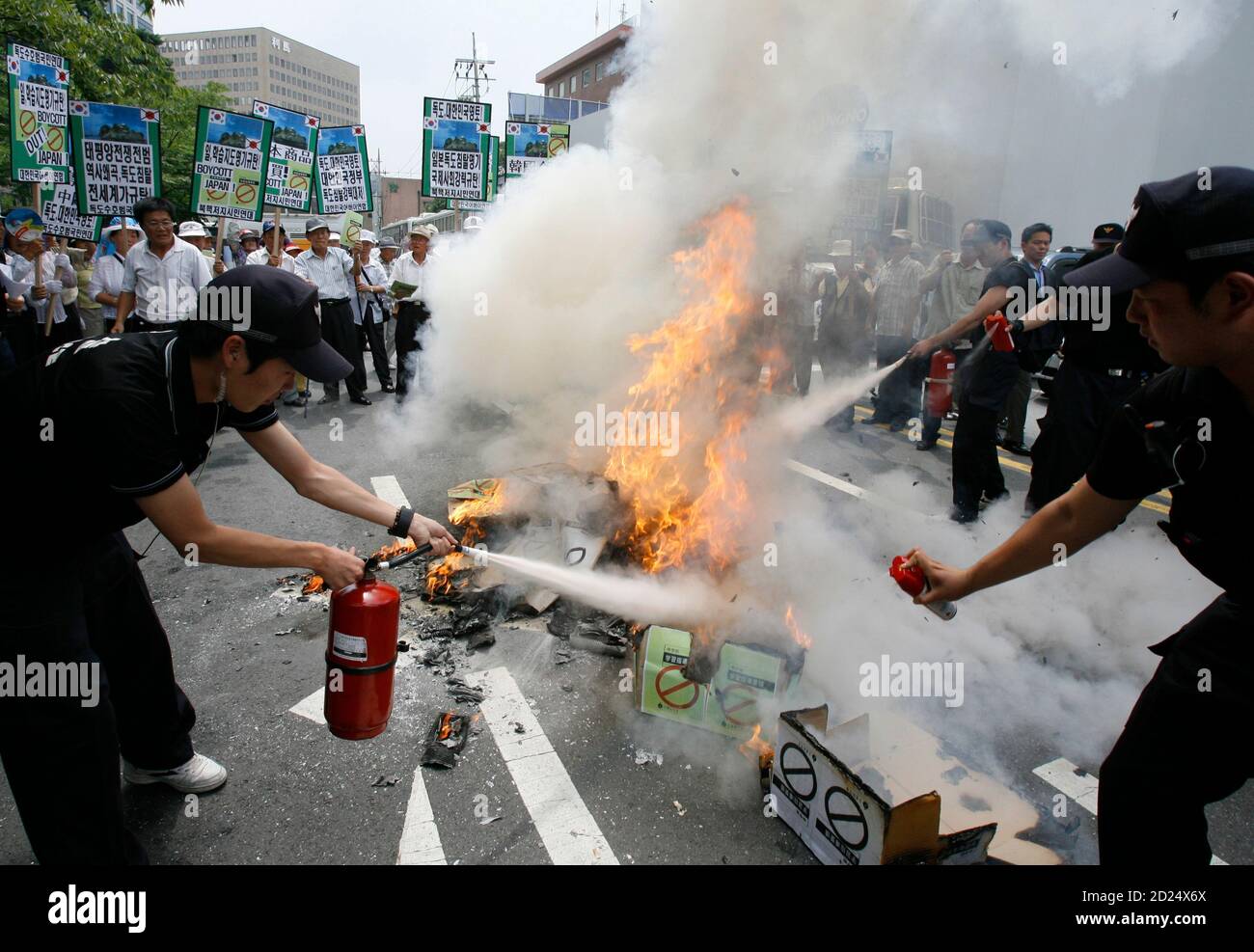 Policemen use fire extinguishers as protesters burn signs representing Japan's middle school teaching guides at a demonstration against Japan's sovereignty claim over a group of desolate volcanic islets Seoul and Pyongyang call Dokdo and Tokyo calls Takeshima, in front of the Japanese embassy in Seoul July 15, 2008. South Korea's coastguard said on Tuesday it had stepped up patrols near the islands, a day after Seoul recalled its ambassador in anger at new Japanese claims to the rocky outcrops. On Monday, Tokyo said it had told Seoul that it would refer in a middle school teaching guide to the Stock Photo