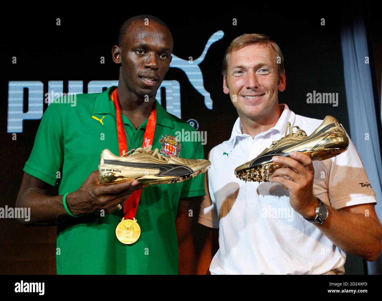 Usain Bolt of Jamaica (L) and Jochen Zeitz, CEO and Chairman of the Board  of Puma, show Bolt Puma shoes during a news conference in Beijing August  23, 2008. REUTERS/Gil Cohen Magen (