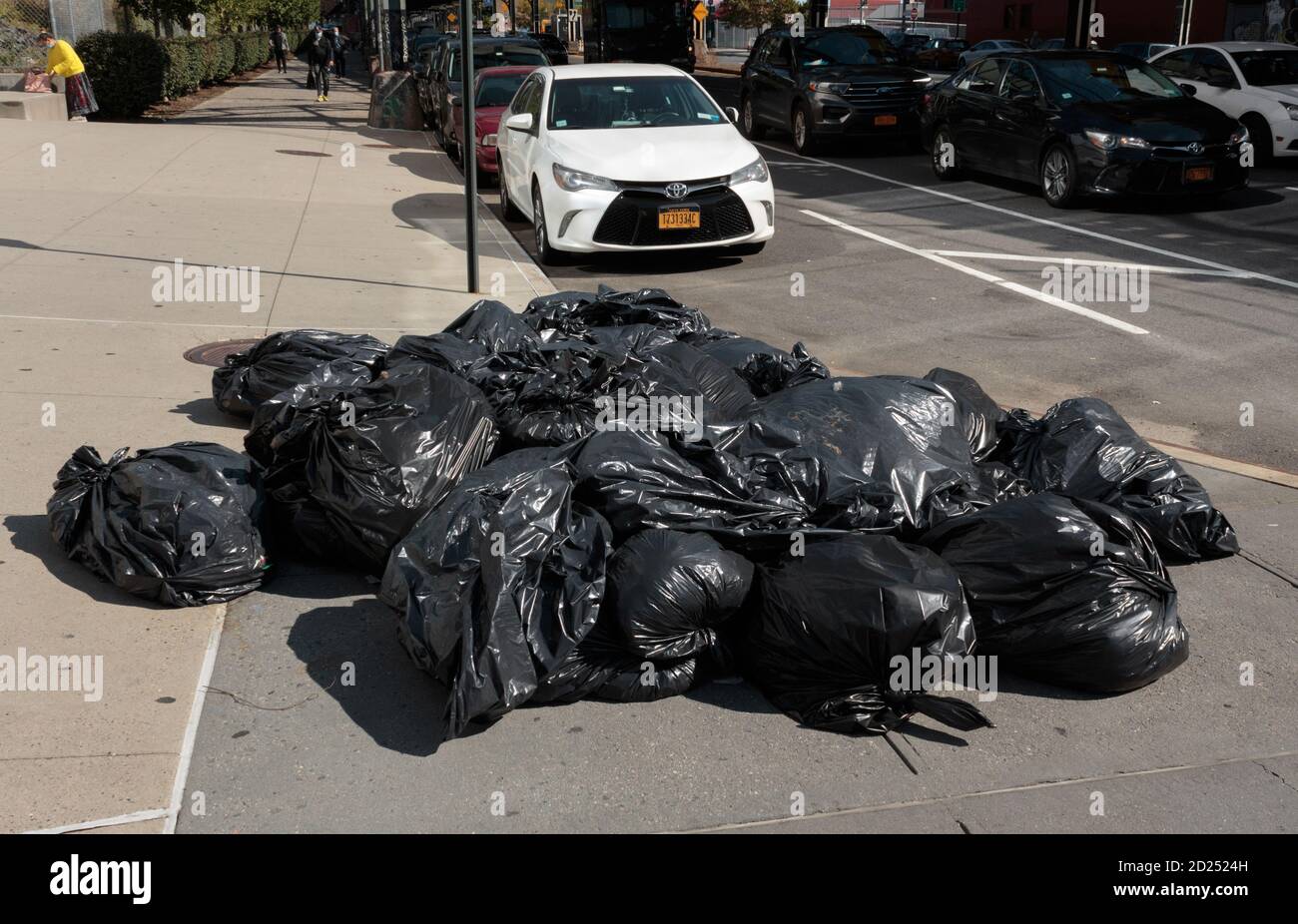 a pile of full plastic garbage bags sitting on a new york city street corner waiting for pickup Stock Photo