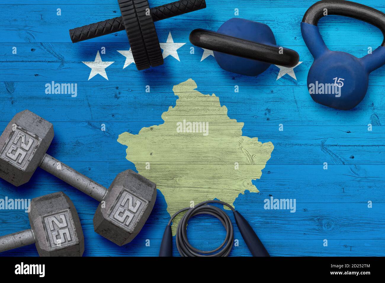Kosovo sports club concept. Top view of heavy weight plates with iron bar on national background. Stock Photo
