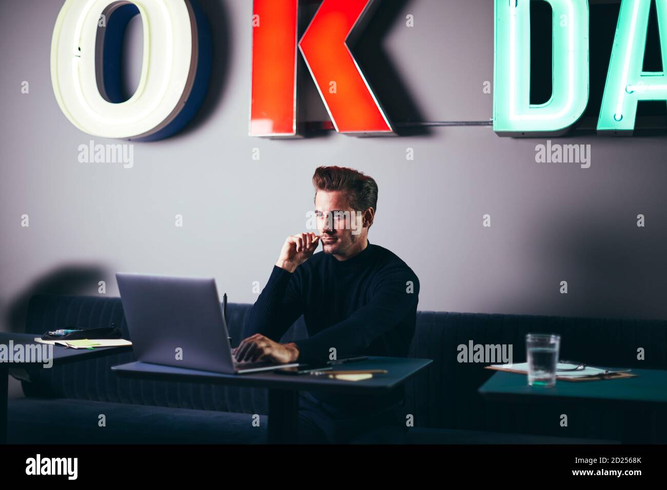 Focused young businessman using a laptop at a table while working in a shared office space Stock Photo