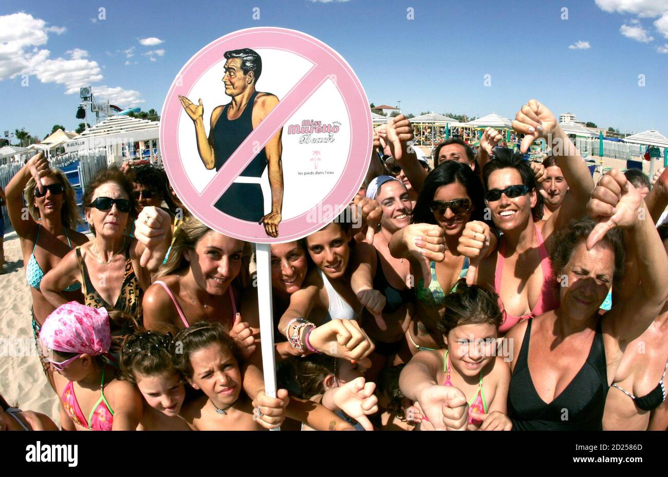 Patrons of a beach, exclusively for women, pose with a sign indicating to bar men from visiting it in the Italian Adriatic resort town of Riccione June 27, 2007. Owners of a seaside complex in Riccione on Italy's Adriatic coast have come up with the perfect solution for women tired of those famous Italian amorous stares -  a stretch of sand where men are banned.         REUTERS/Daniele La Monaca    (ITALY)   BEST QUALITY AVAILABLE Stock Photo