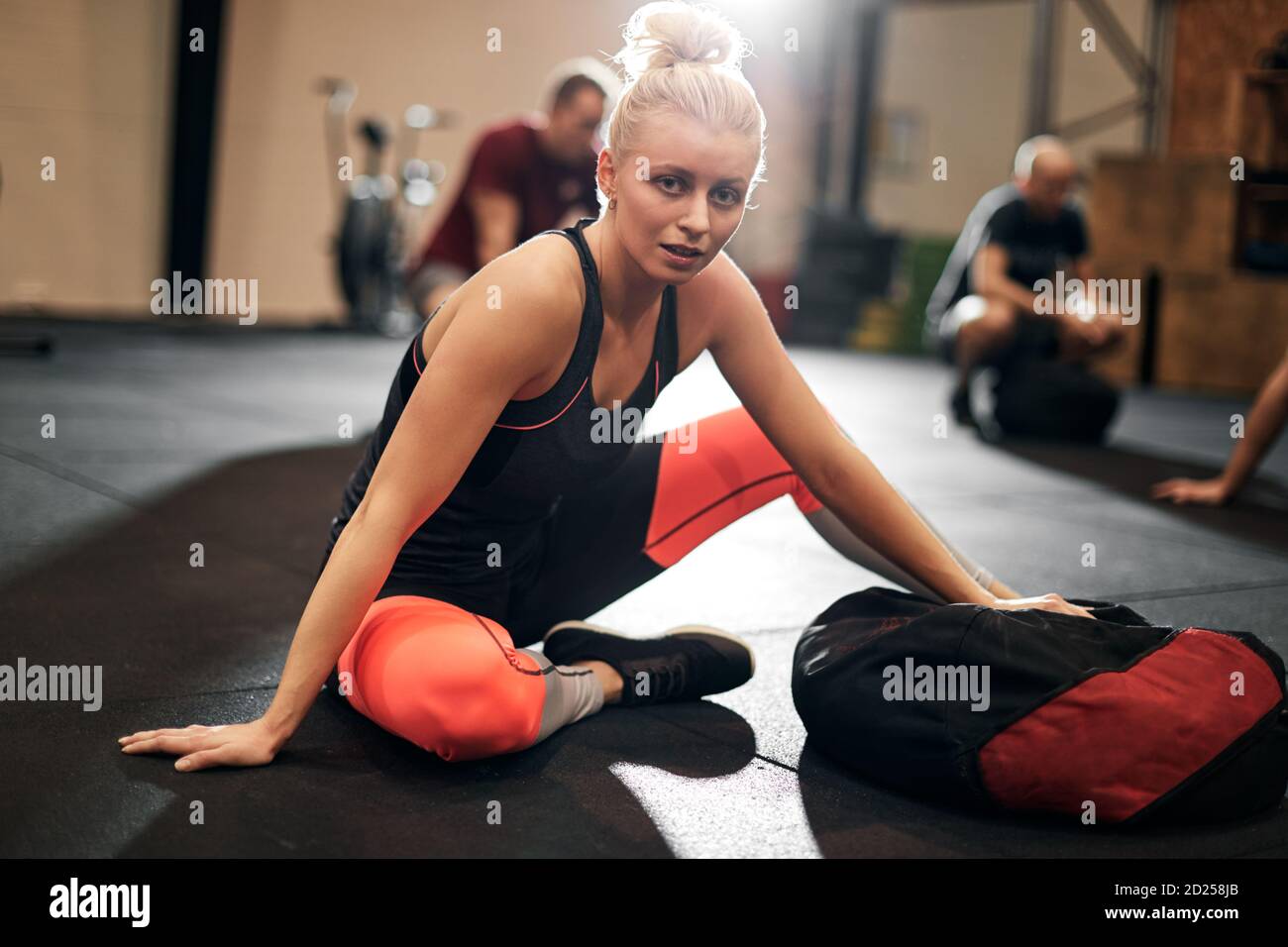 Fit young woman in sportswear sitting on a gym floor after an exercise ...