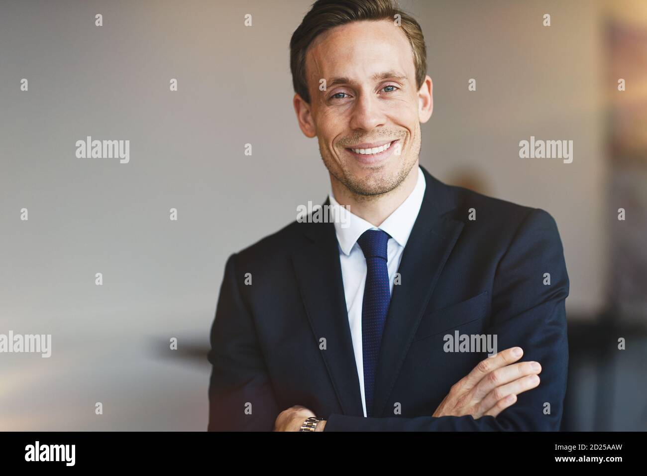 Confident young businessman in a suit smiling while standing with his ...