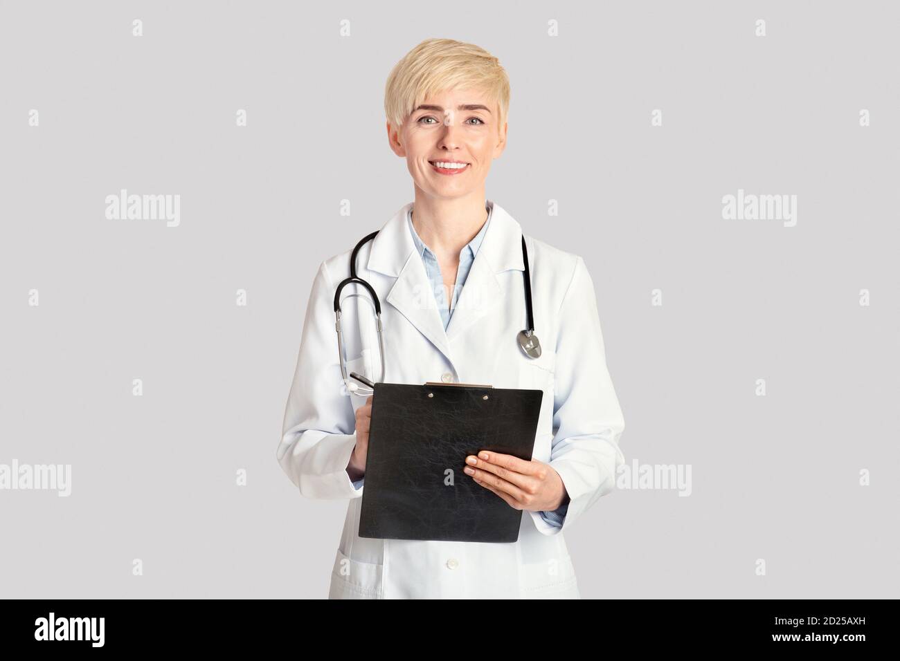 Medical professions, healthcare and prevention concept. Smiling adult woman making notes in tablet Stock Photo