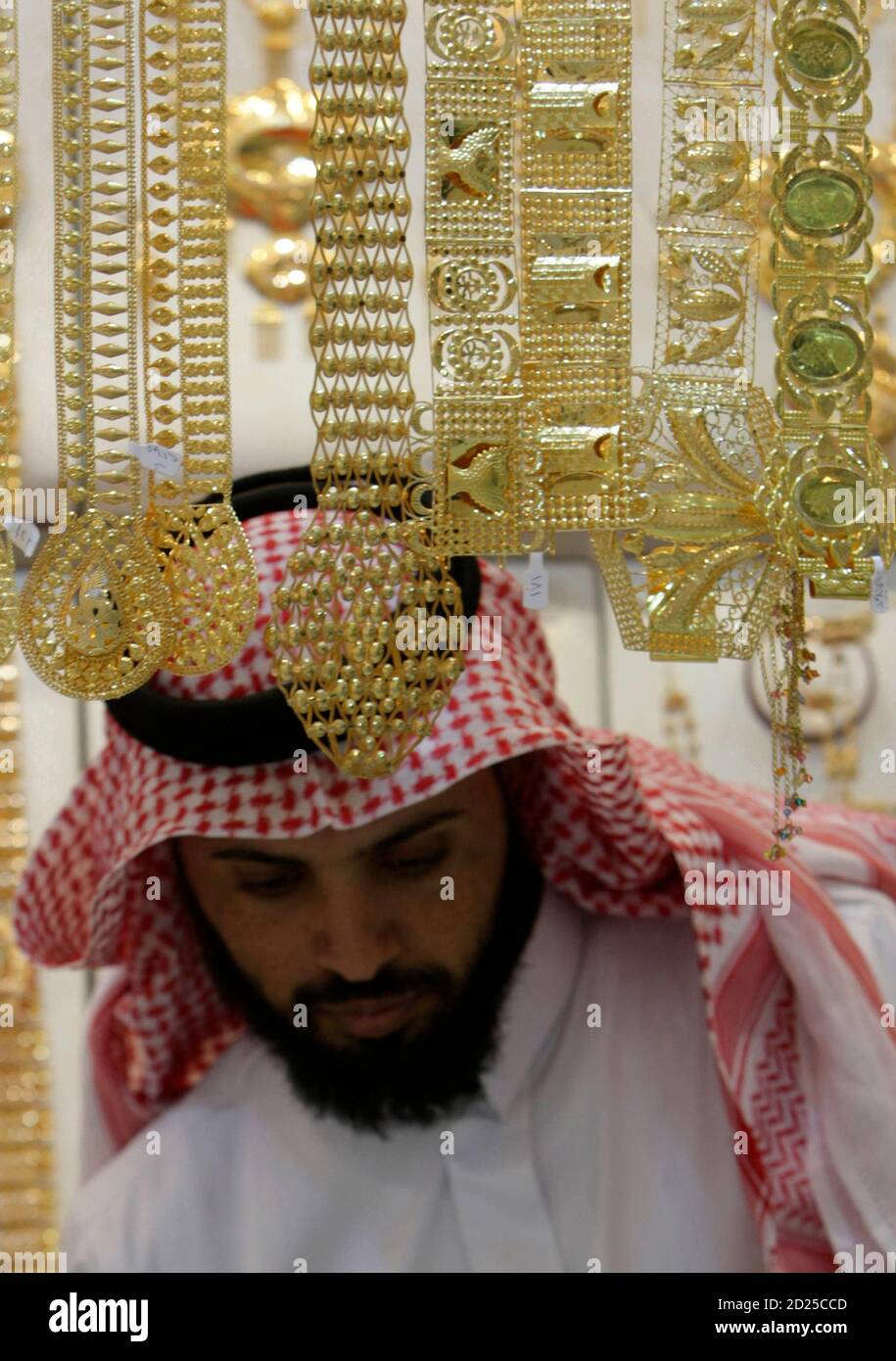 A salesman arranges gold necklaces at a 
