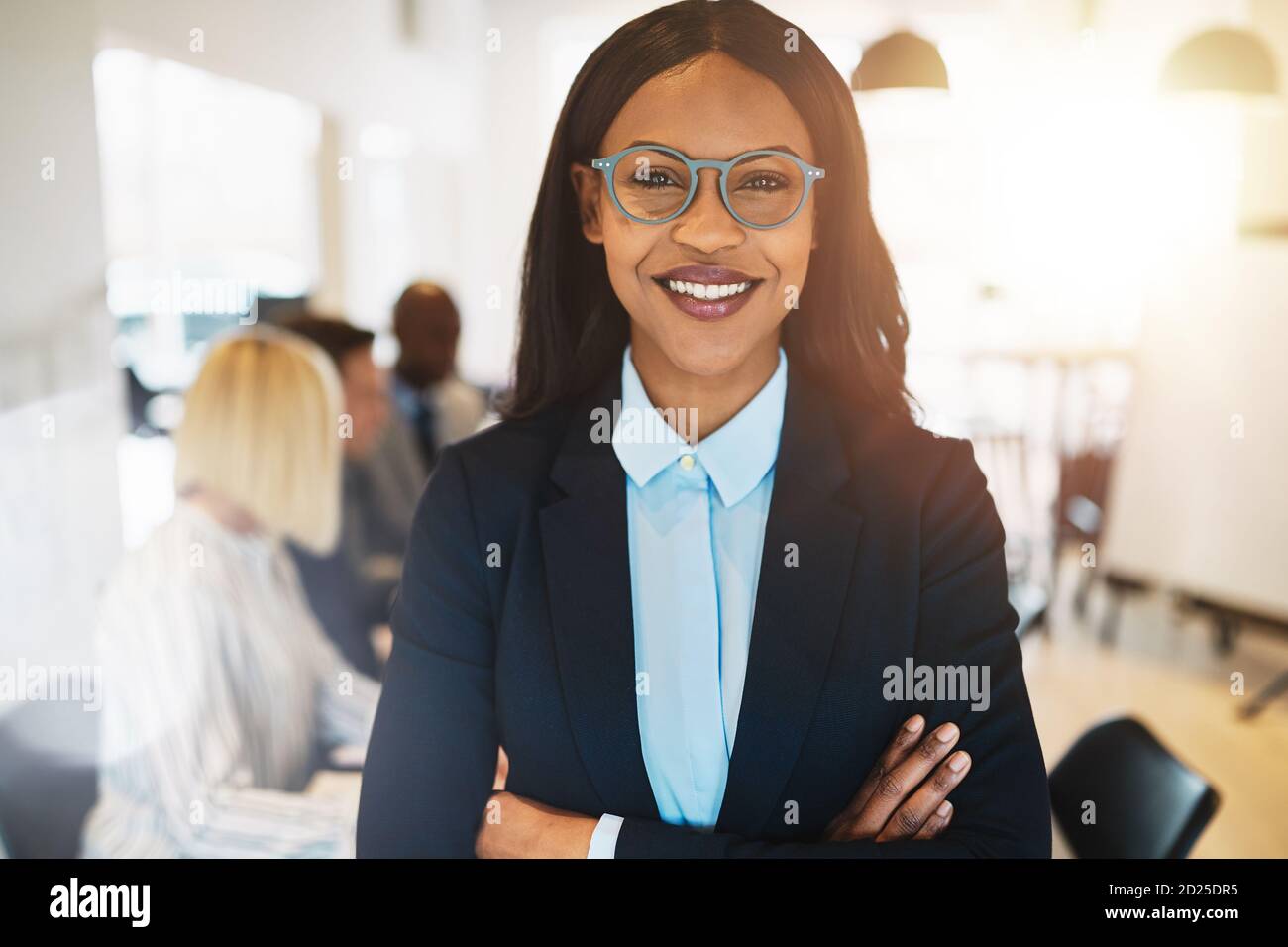 Young African businesswoman standing with her arms crossed in an office ...