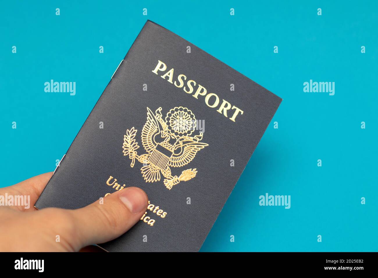 Hand holding US Passport on blue background Stock Photo - Alamy
