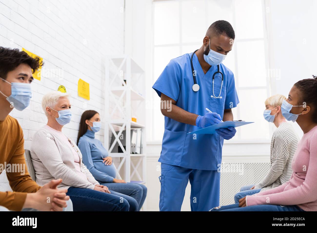 Doctor Working With Diverse Patients In Hospital During Coronavirus Vaccination Stock Photo