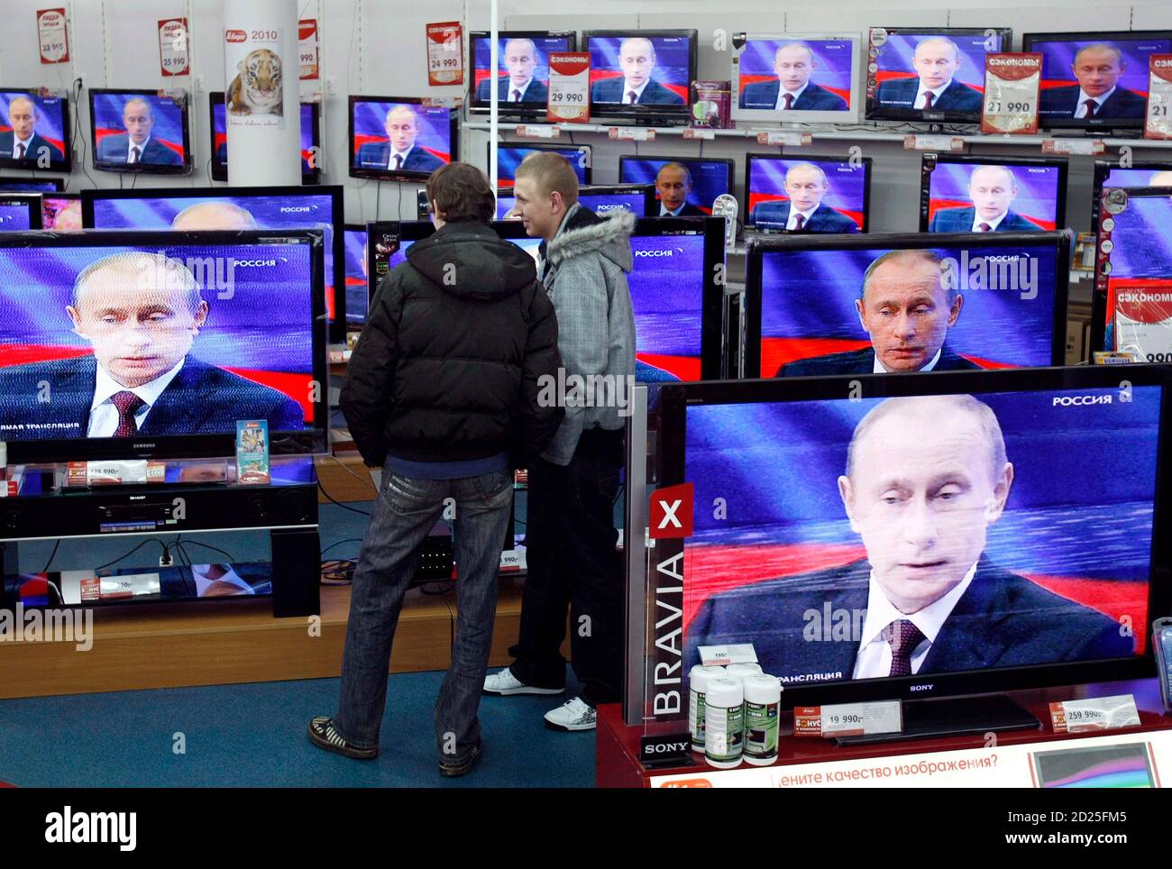 Men look at a television screening of Russia?s Prime Minister Vladimir  Putin as he speaks during a question-and-answer show at a Russian state TV  channel, at an electronics shop in Moscow December