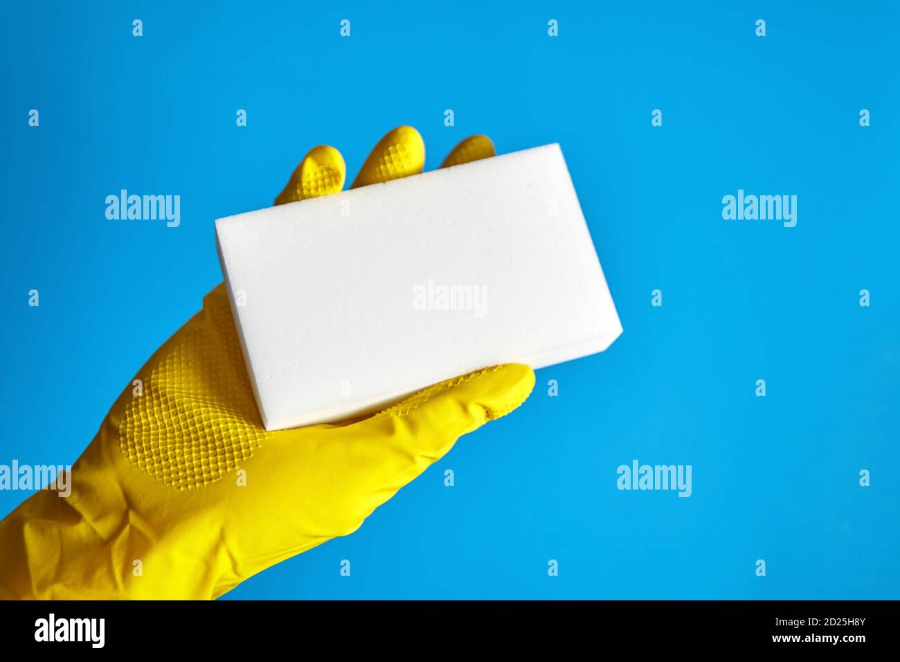 Human hand in yellow glove holds a white melamine household sponge on ...