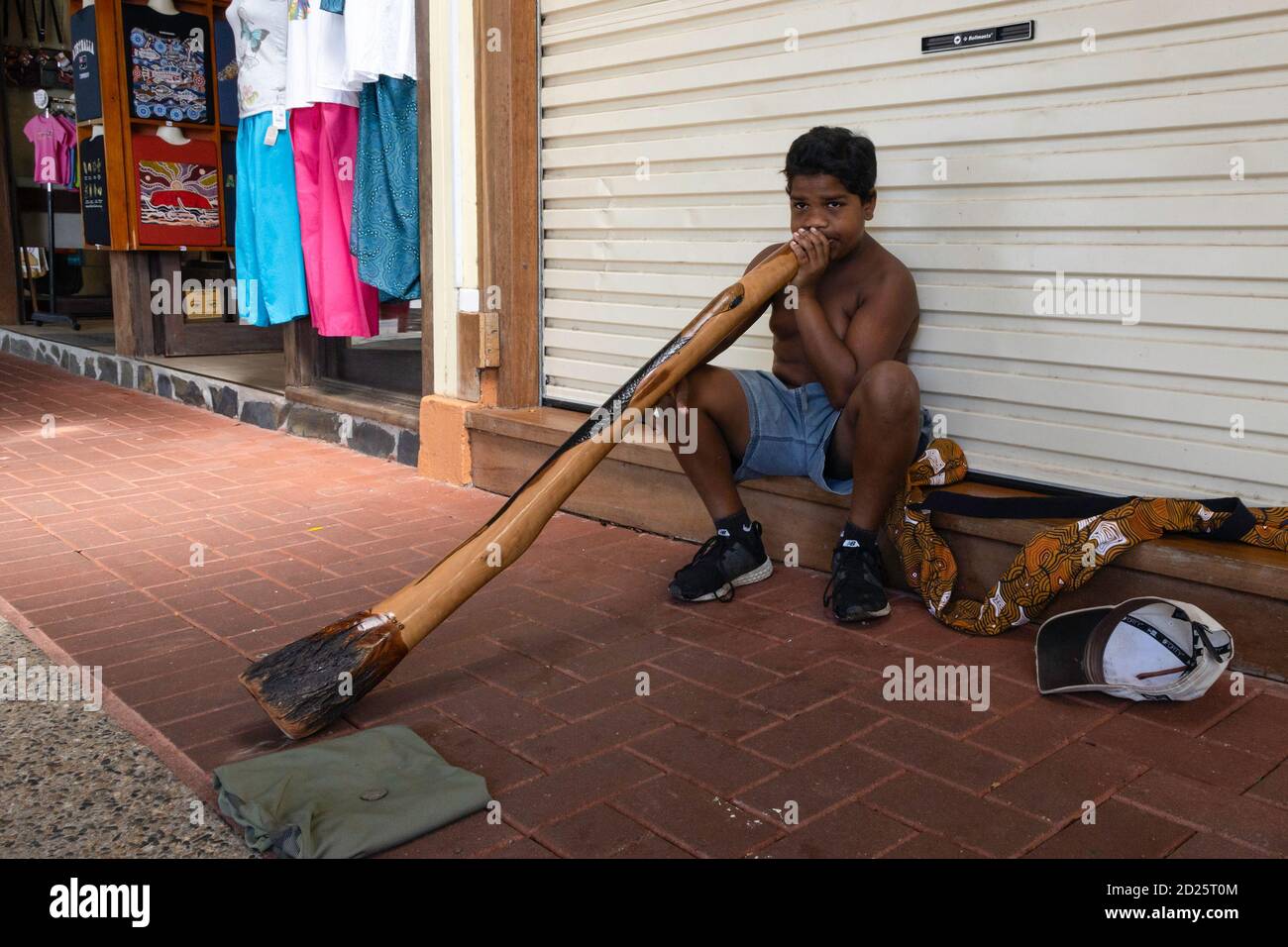 Kuranda, Australia - March 19th, 2020: A young native australian playing a didgeridoo on a Kuranda, Australia, sidewalk. Stock Photo