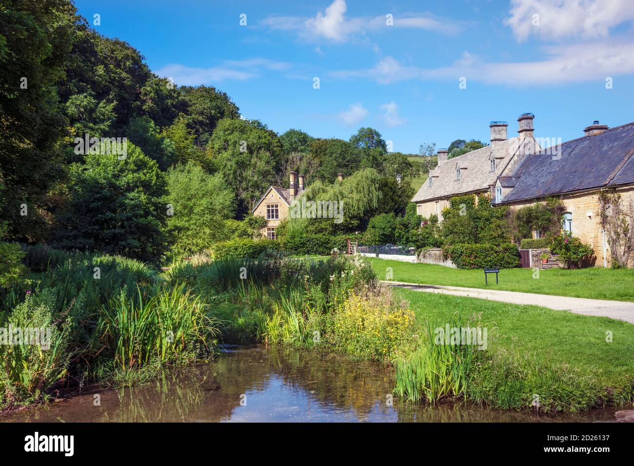 UK, Gloucestershire, Cotswolds. Summer view of a stream and traditional cottages in the village of Lower Slaughter near Stow-on-the-Wold Stock Photo