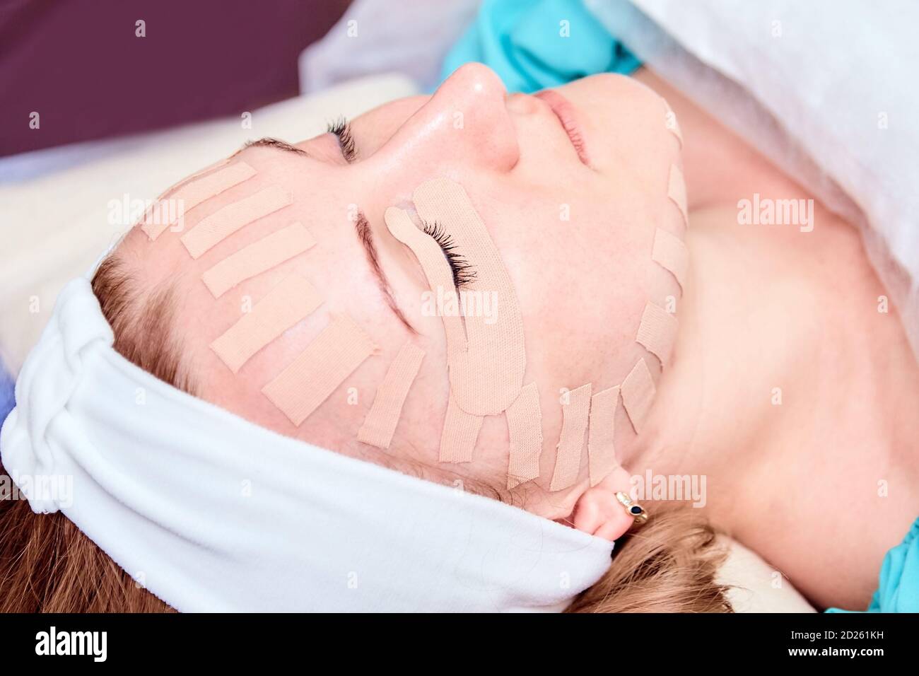 Kinesiotaping. Young woman lying with tape on her face. Physiotherapy and cosmetology procedure. Method of non-surgical skin rejuvenation. Facial skin Stock Photo