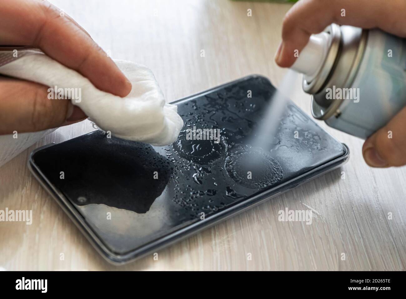 man wipes his mobile phone with rag. Disinfecting alcohol solution for
