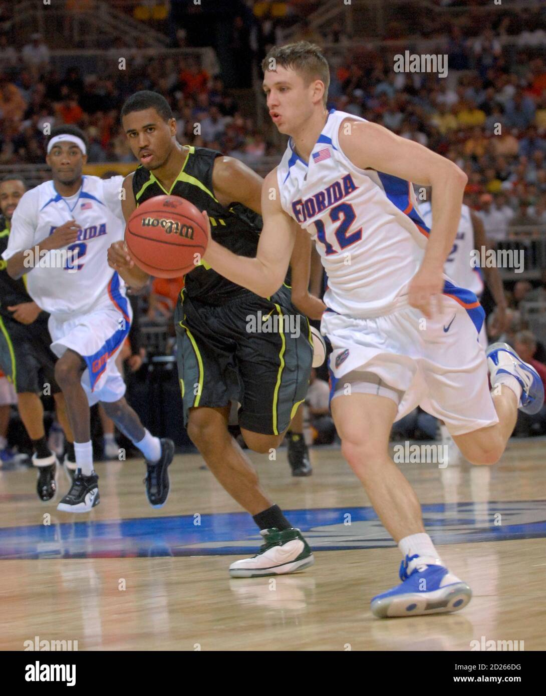 University of Florida Gators' Lee Humphrey (R) dribbles the ball past  University of Oregon Ducks' Bryce Taylor (C) as Gators player Corey Brewer  watches on in their NCAA men's Midwest Regional final
