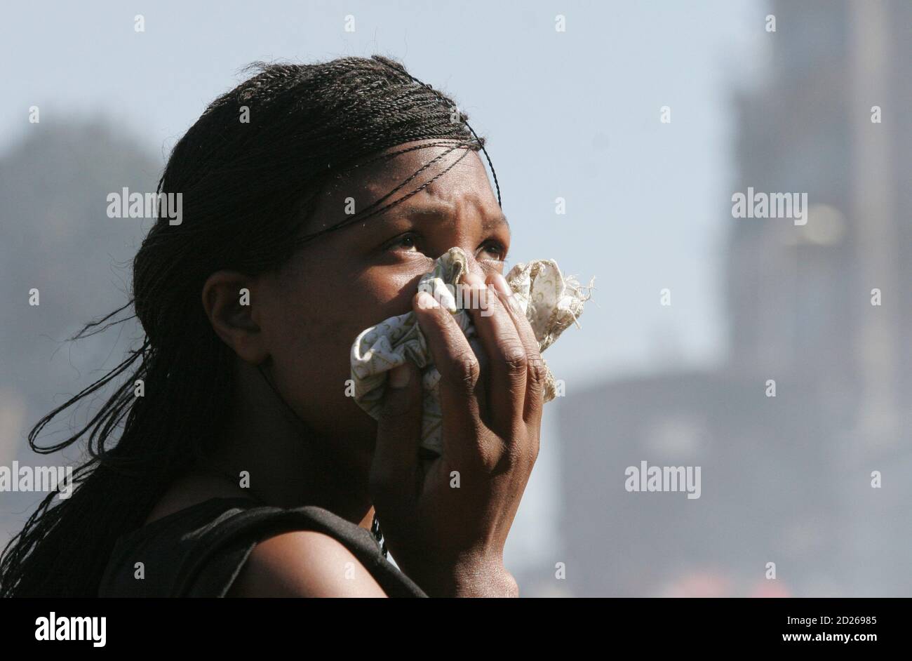 A woman covers her face to protect from teargas during ethnic violence in Nairobi January 2, 2008. President Mwai Kibaki's government accused rival Raila Odinga's party of unleashing 'genocide' in Kenya on Wednesday as the death toll from tribal violence over a disputed election passed 300. REUTERS/Thomas Mukoya   (KENYA) Stock Photo