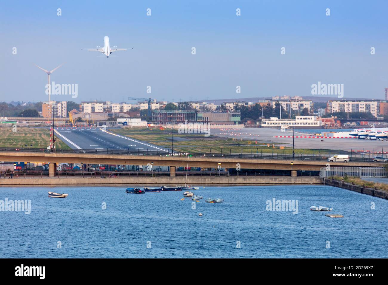 A jet aircraft taking off from London City Airport in front of the 19th Century Royal Victoria Dock Stock Photo