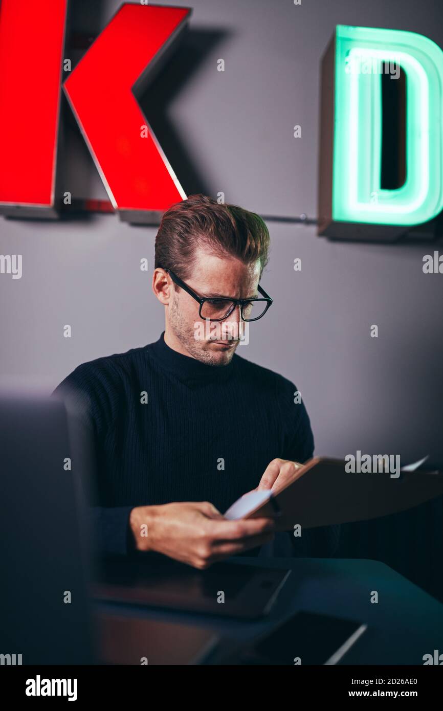 Young businessman going over documents on a clipboard while sitting at his desk in a modern office Stock Photo