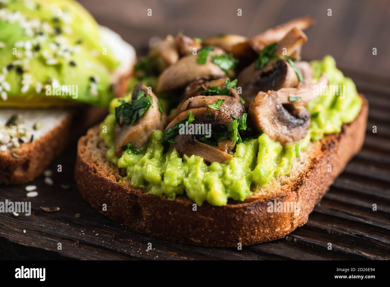 Tasty avocado toast with fried mushrooms and greens Stock Photo