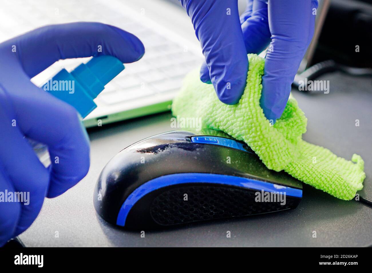 woman disinfects the computer mouse with a disinfectant liquid ...