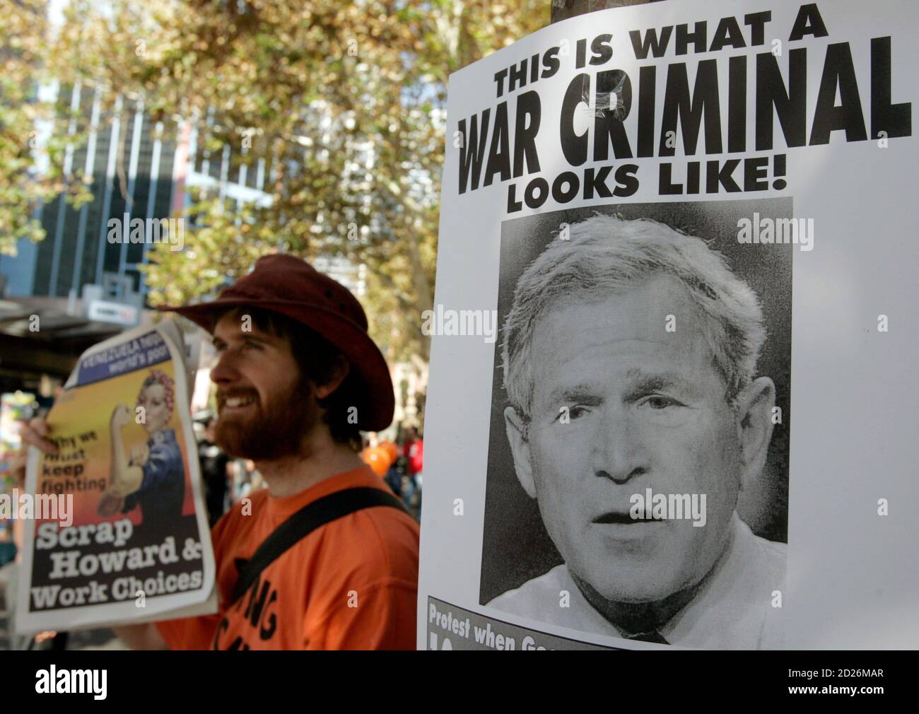 A sells newspapers near a poster of U.S. President Bush in Sydney before a demonstration to free Australian Guantanamo Bay David Hicks April 21, 2007. The demonstration is part