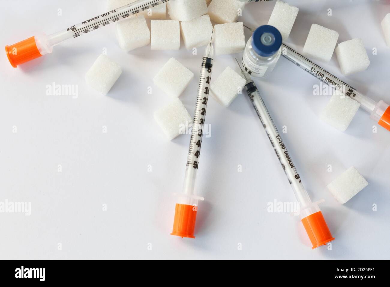 Sugar addiction, insulin resistance, unhealthy diet, sugar cubes pyramid, bottles of insulin and syringe for vaccinationon white background, diabetes Stock Photo
