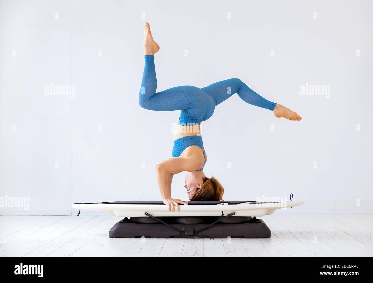 Sporty woman doing a headstand on a surfset board in a side view