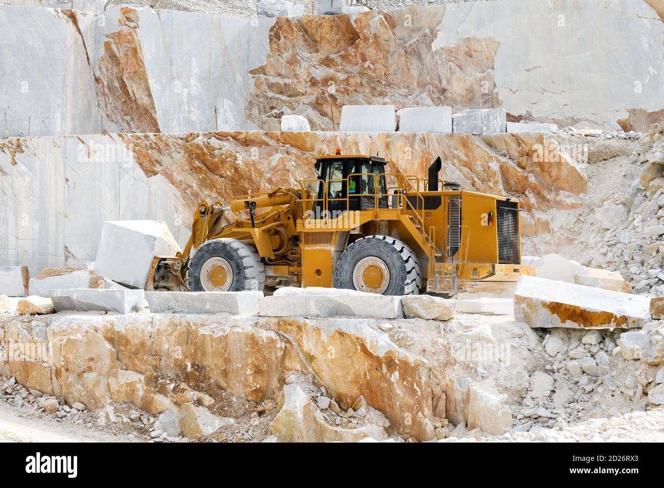 Heavy duty front end loader transporting marble in an open cast quarry or mine in Carrara, Tuscany, Italy during extraction of the rock from a mountai Stock Photo