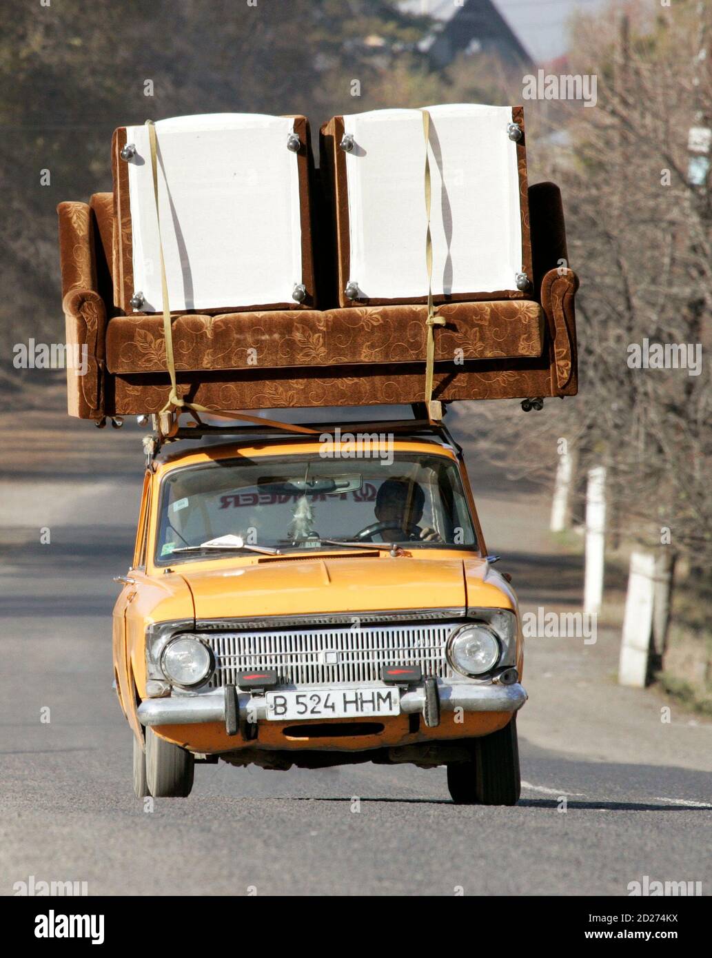 A man drives a car with a couch strapped to its roof on a road some 50 km (31 miles) east of Almaty, Kazakhstan, November 15, 2006. Many Kazakhs were upset by the British comedian Sacha Baron Cohen's film about the fictional TV journalist Borat, an anti-Semitic misogynist, who calls Kazakhstan his home. In an interview with Rolling Stone magazine released on Wednesday, Baron Cohen, 35, said he was surprised the film had caused such offence in Kazakhstan or that its humour had been so misinterpreted.  Picture taken November 15, 2006.  REUTERS/Shamil Zhumatov (KAZAKHSTAN) Stock Photo
