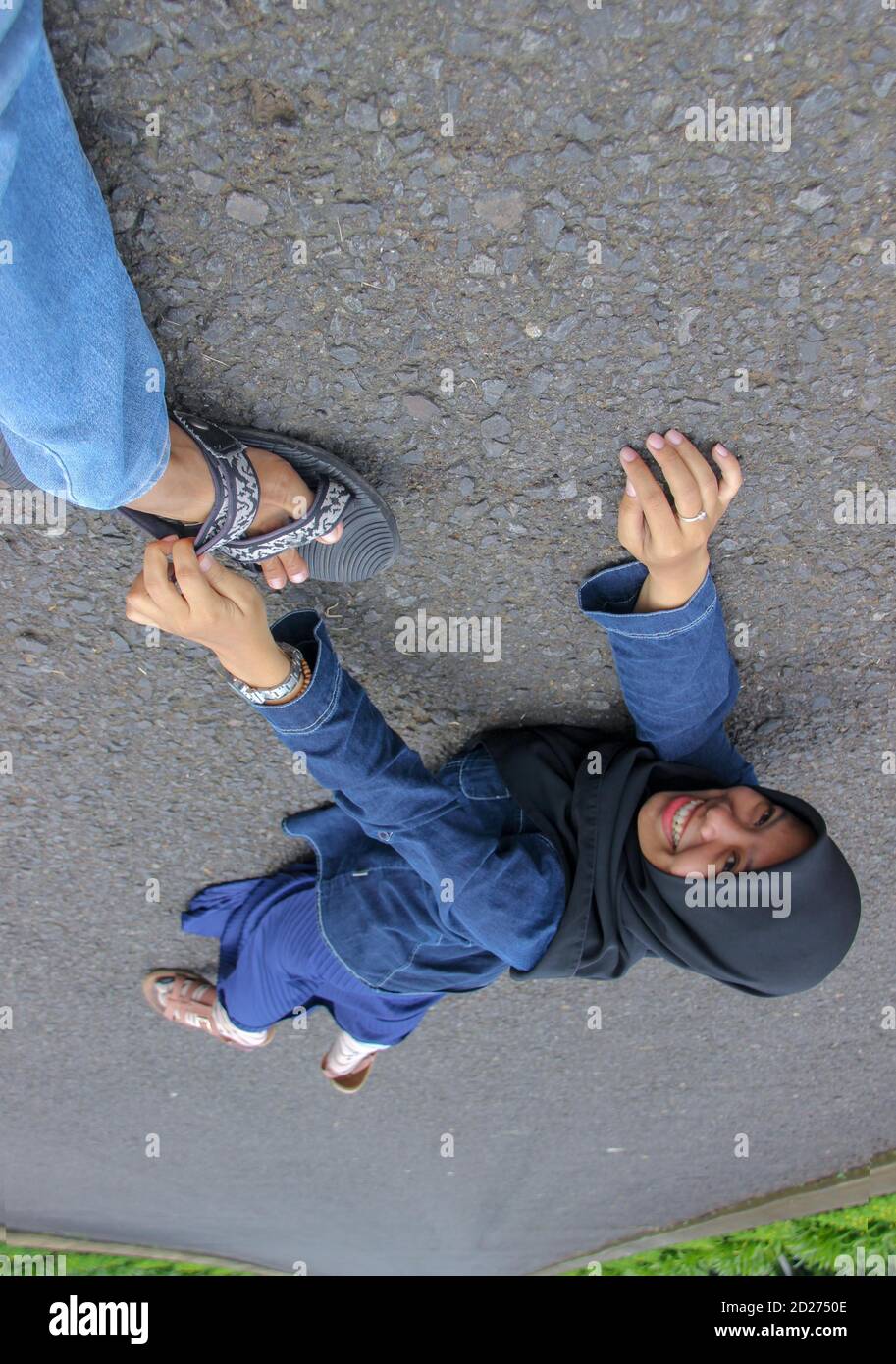 Asian woman portrait of foot grip with cute and creative concept. woman lying on the highway with an expression of happy laughter. Stock Photo