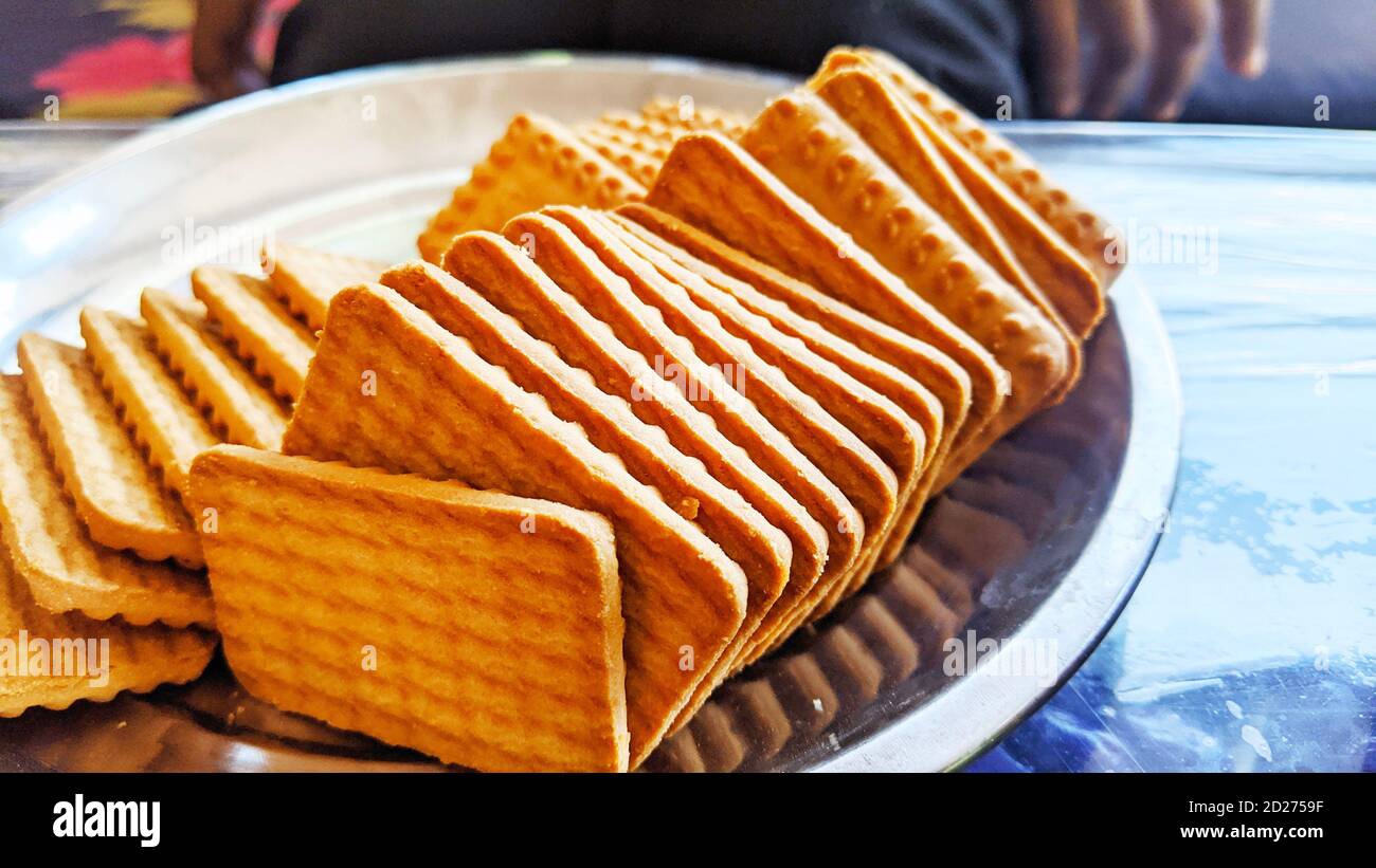 Wheat biscuits in the steel plate with blury background. Indian biscuits popularly known as Chai-biscuit in India Stock Photo