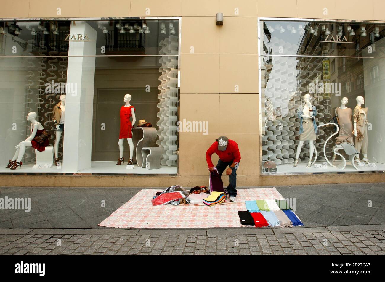 A hawker sets up his stall outside a Zara shop in central Seville March 25,  2009. Europe's biggest clothing retailer Inditex SA expects to outperform  the industry in 2009 and will continue