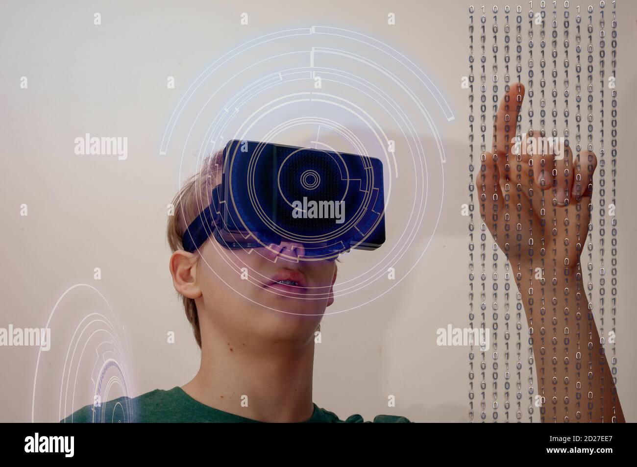 Young man using virtual reality glasses or headset working on virtual screen with data stream and hud Stock Photo