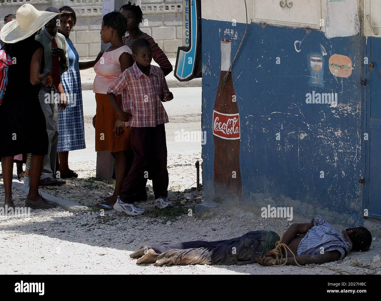 Haitian boy looks at at a body, which has its hands tied up, in the neighborhood of Bel-Air in Port-Au-Prince, Haiti September 20, 2005. Two men were stoned and hacked to death in the volatile neighborhood on Tuesday. A resident who said he witnessed the killings, said the victims belonged to armed gangs and were attacked by the neighborhood's residents. REUTERS/Eduardo Munoz Stock Photo