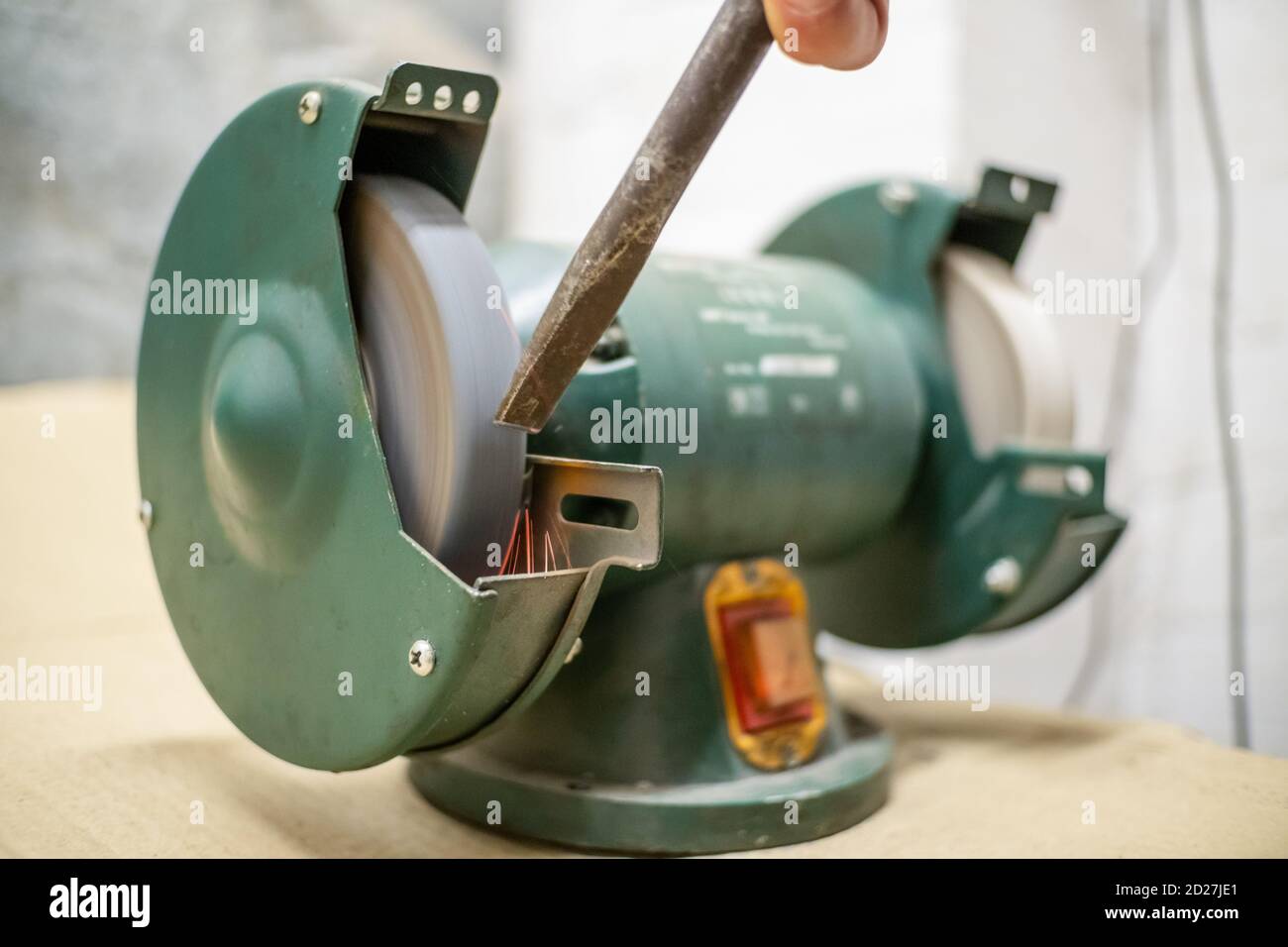 master sharpens a chisel on a grinding machine Stock Photo