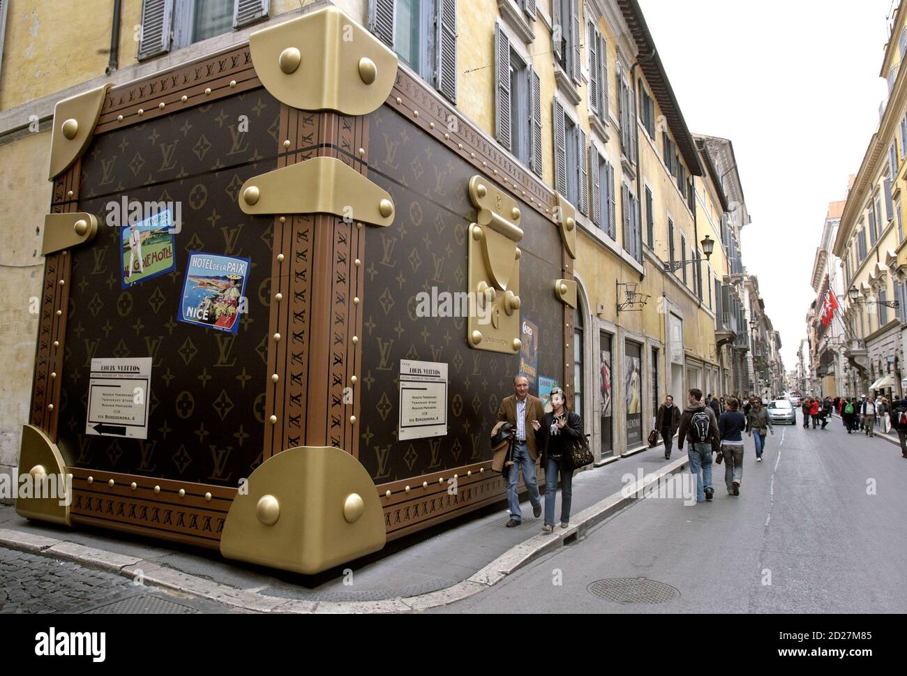 Tourists pass a Louis Vuitton shop closed for refurbishment, its facade  covered with a faux suitcase, in central Rome March 29, 2007. REUTERS/Chris  Helgren (ITALY Stock Photo - Alamy