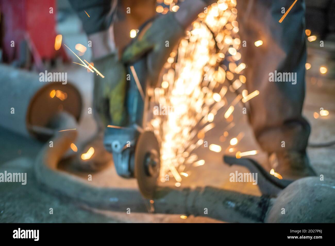engineer-technologist working on cutting metal and steel bar with angle grinder, parts of metallurgical plant. photo out of focus Stock Photo