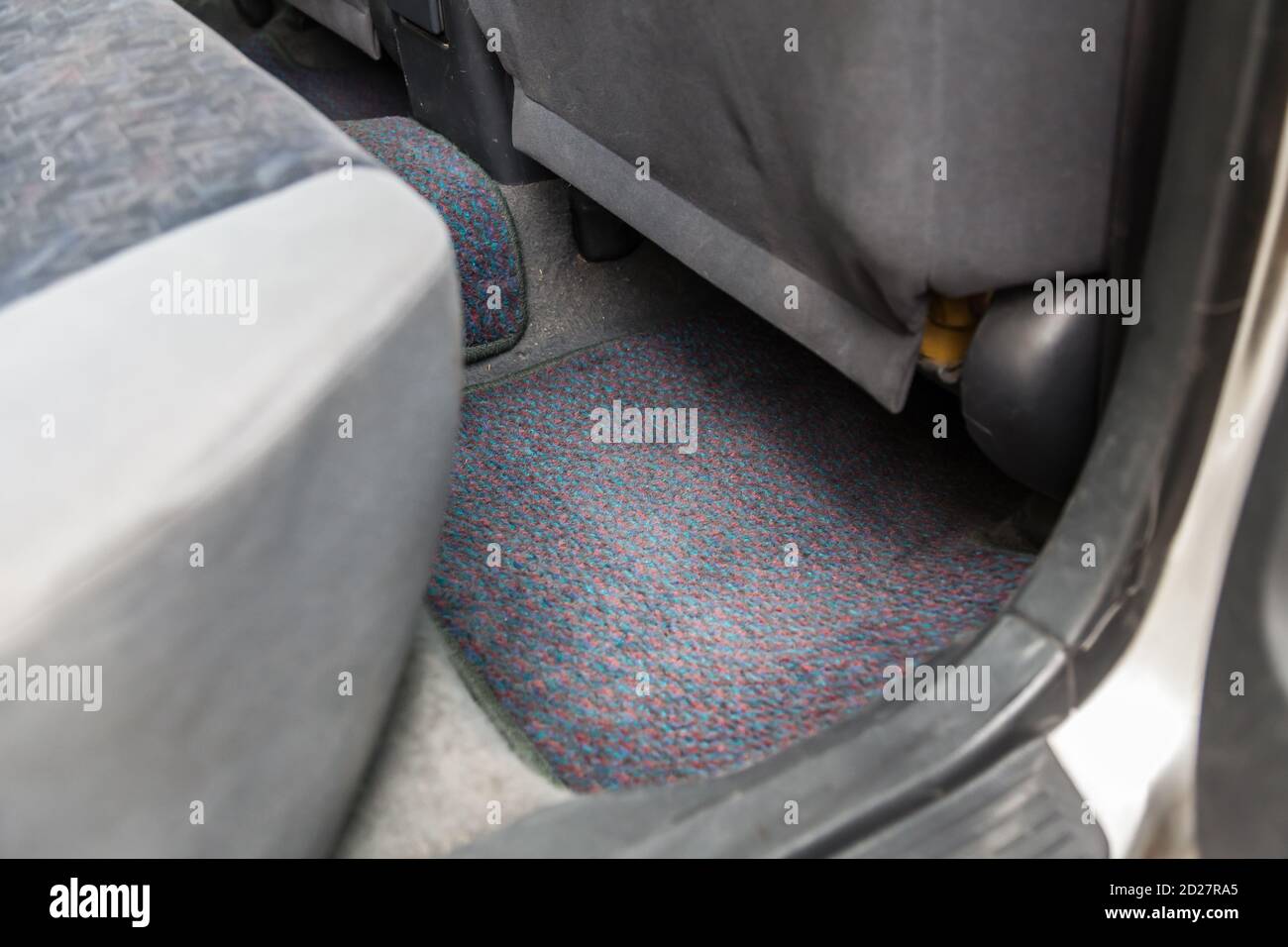 Clean car floor mats of black carpet under rear passenger seat in the