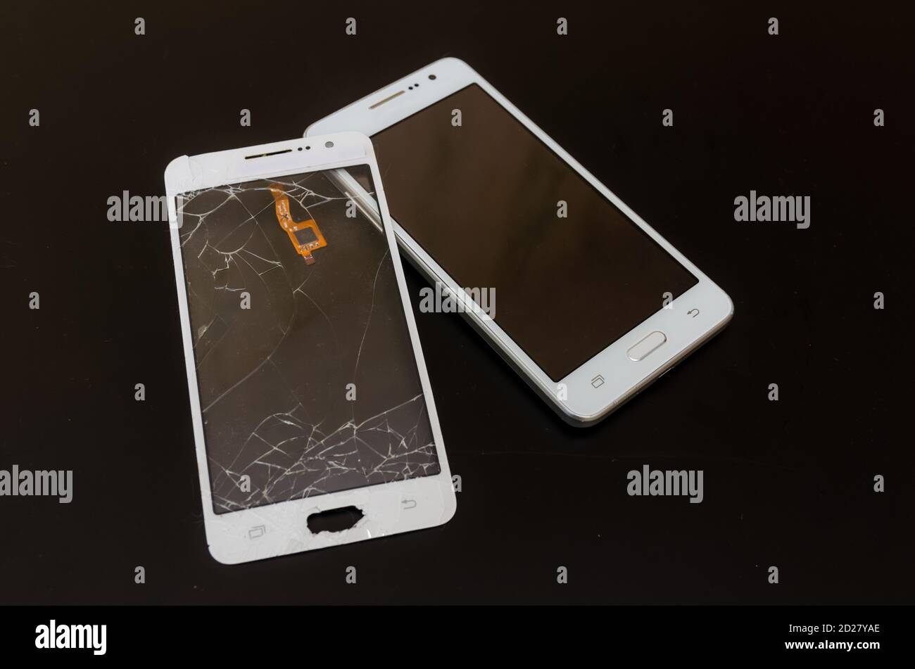 Smartphone after repairing a cracked touch screen. Nearby is a cracked touch screen. Black background with copy space. Stock Photo