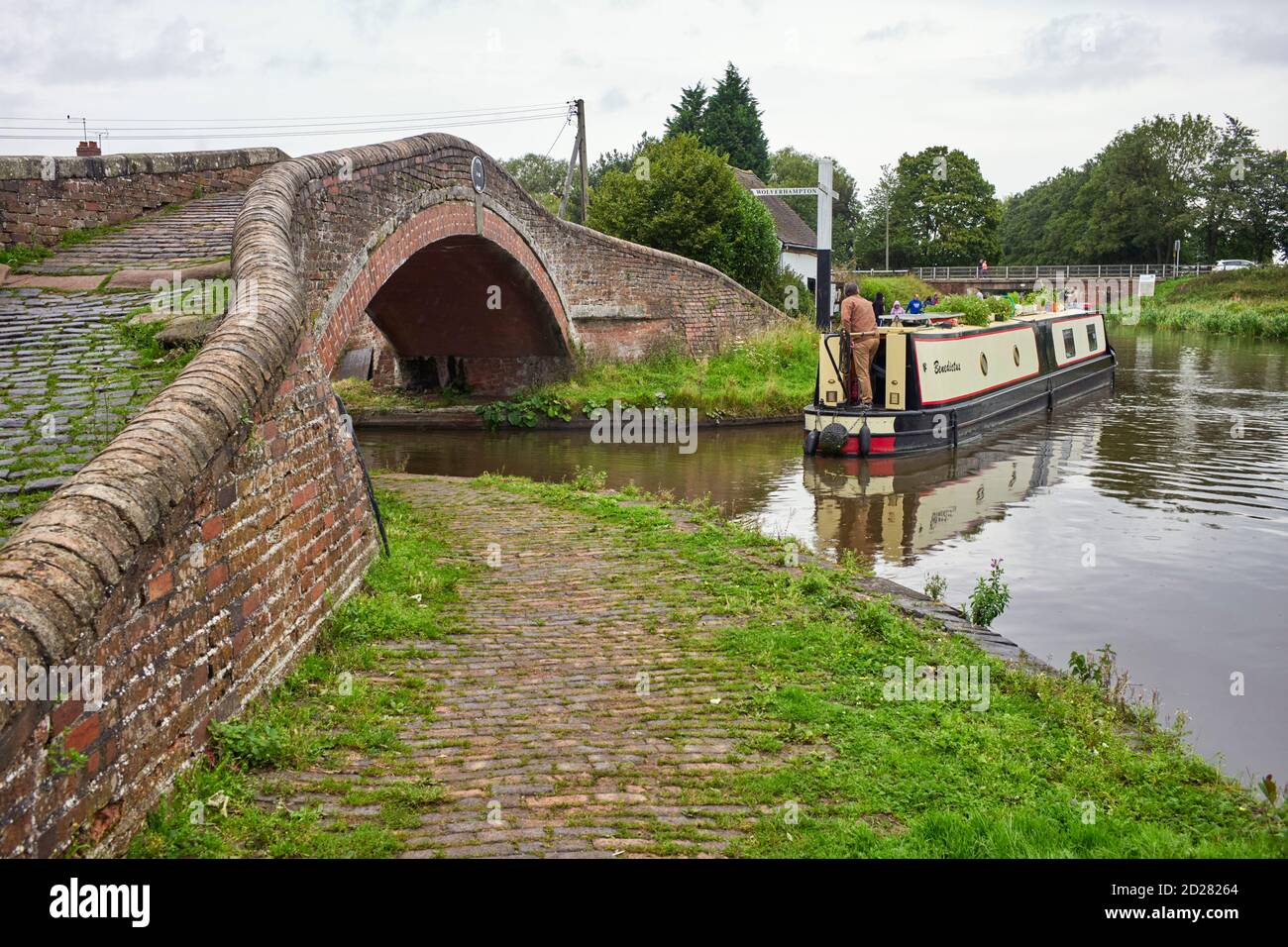 A narrowboat making the sharp turn onto the Trent and Mersey canal under the bridge at Great Haywood Stock Photo