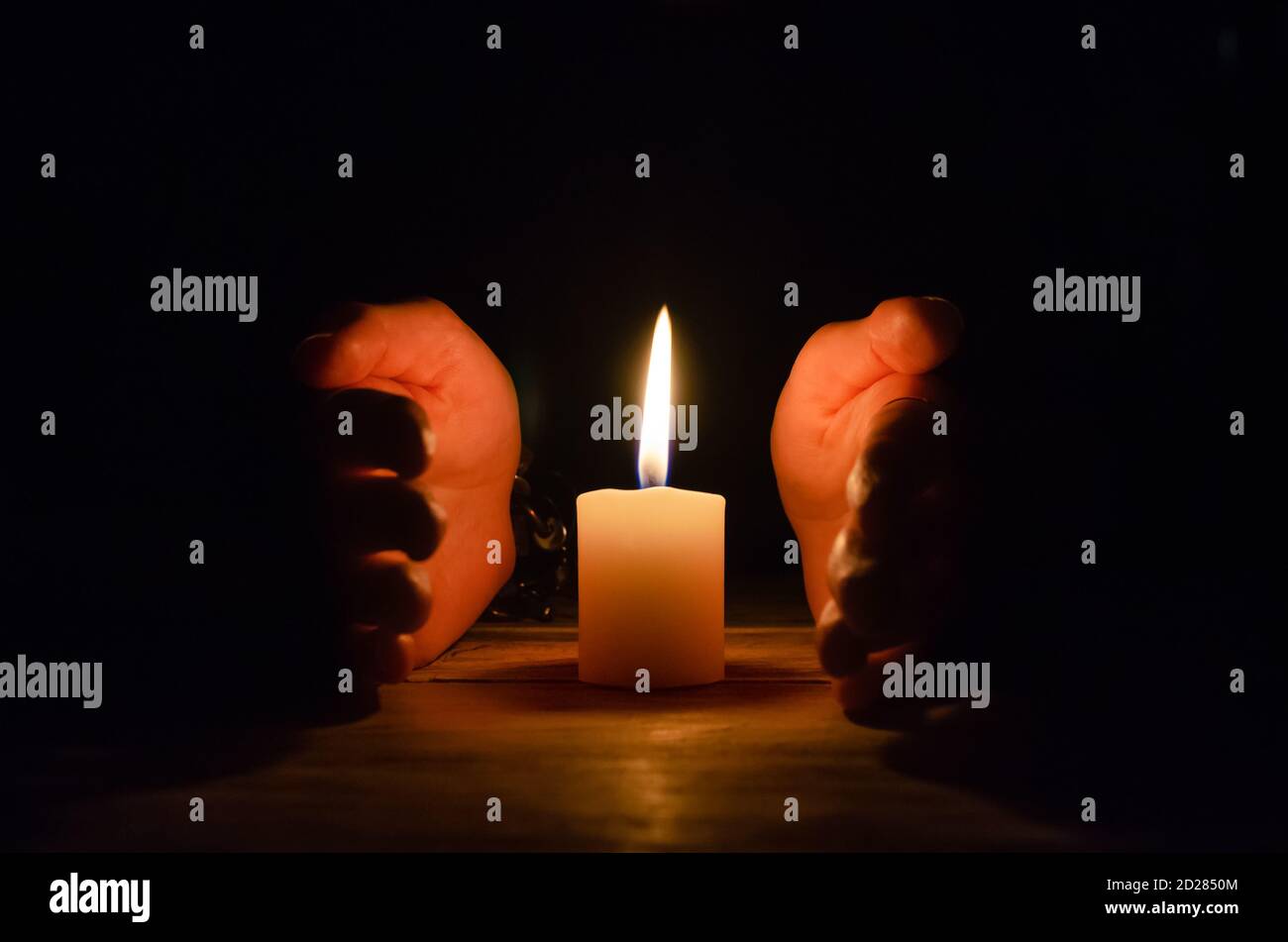 Hands wrapped around a large candle close-up, copy space Stock Photo