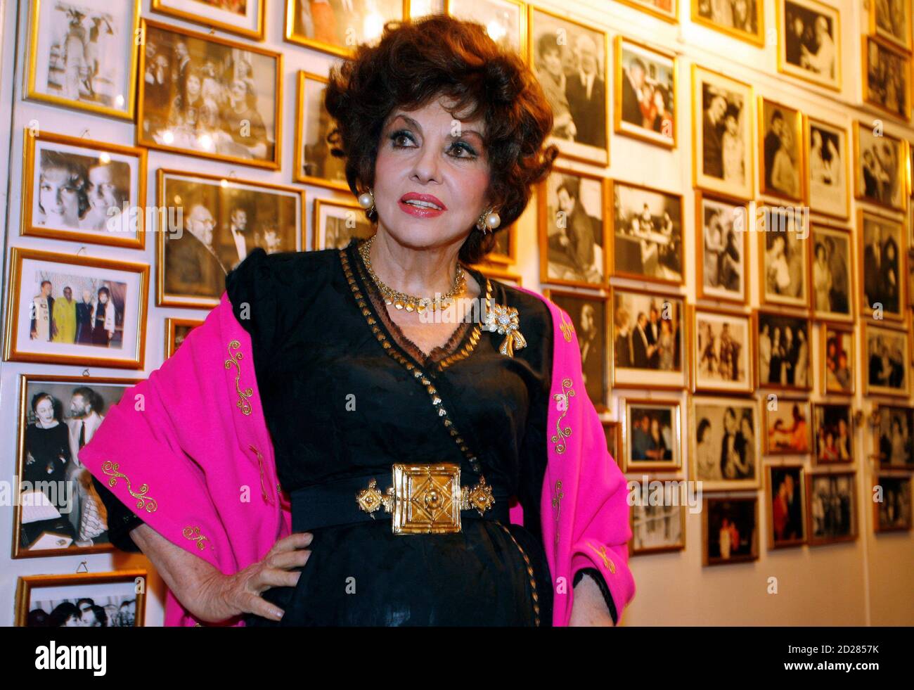 Italian film icon Gina Lollobrigida poses near a wall of celebrity photos in her villa in southern Rome December 7, 2006. Lollobrigida vowed on Thursday to make the media pay for ruining her plans to marry Javier Rigau, a Spaniard 34 years her junior. In an interview with Reuters after she arrived in Rome from Philadelphia, the 79-year-old film star said the couple had called off their wedding plans after Rigau was worn down by 'endless attacks, slander and violence' from the media.    REUTERS/Chris Helgren   (ITALY) Stock Photo