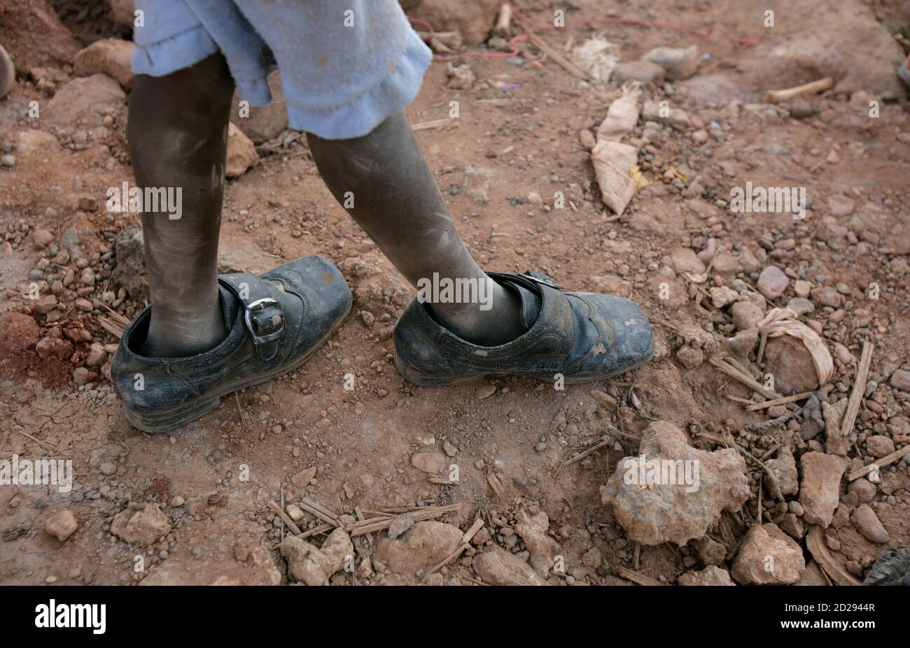 A Sudanese boy walks at playground with oversized shoes during a visit of a  delegation of the German Red Cross and the Sudanese Red Crescent in a  flood-effected area in a Khartoum