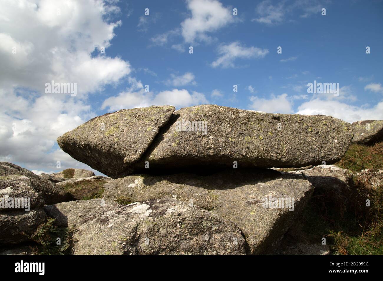 Large lying granite rock with a unique shape against a blue sky and cloudy background. Stock Photo