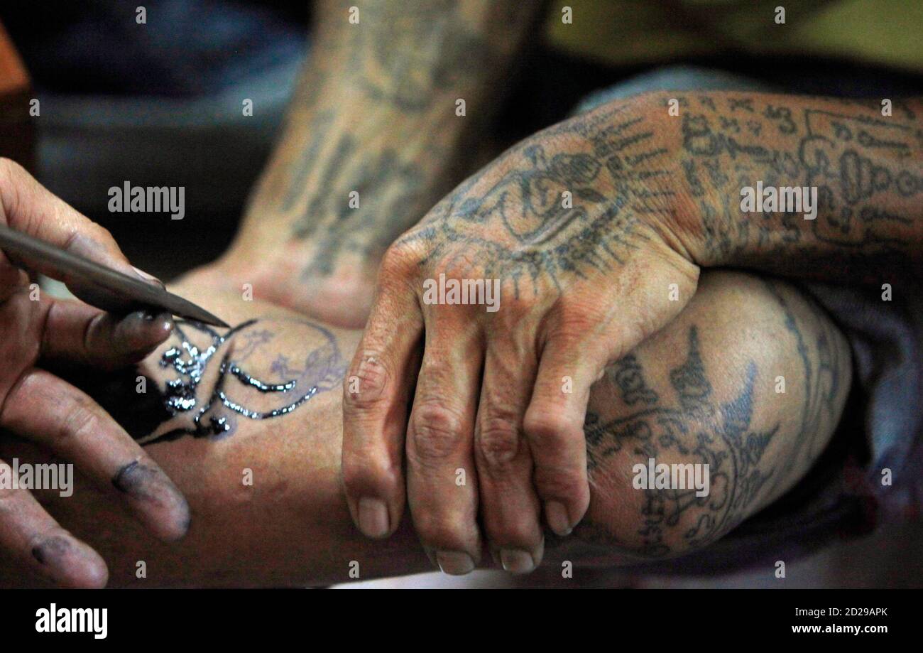 A Buddhist Monk Uses A Needle To Tattoo The Calf Of A Man During The Annual Magic Tattoo Festival At Wat Bang Phra In Nakhon Prathom Province About 80 Km 50 Miles