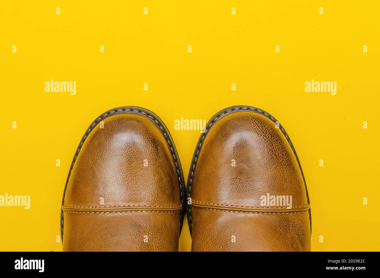 Rounded nose of men's brown shoes on a yellow background close-up with a copy of the space Stock Photo